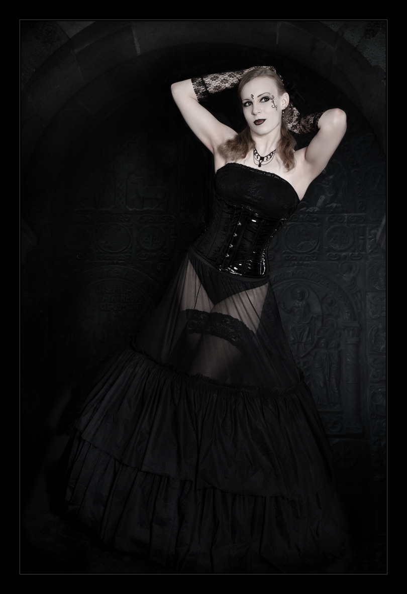 Beautiful model wearing black corsage and a transparent black skirt posing in front of an old black gate - © by Magistus