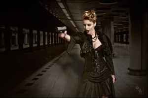 Fighting Vampire - Fantasy Vampire Composing with a great vampire girl in black gothic dress pointing angry with a gun in the underground showing a big cleavage and her fangs. - © by Magistus